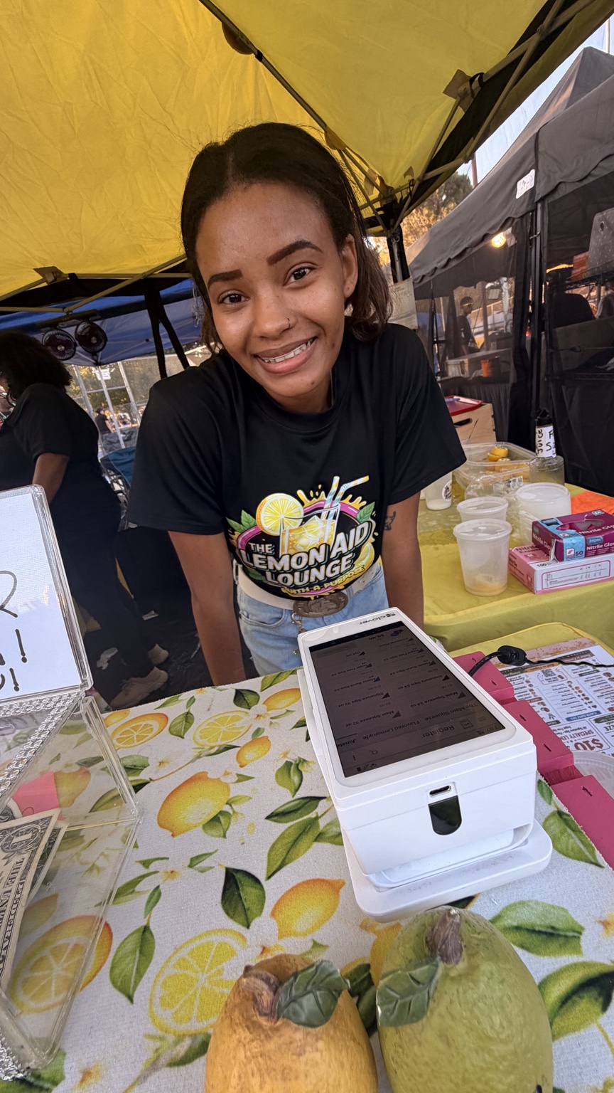 A smiling Lemon Aid Lounge team member welcoming customers at the register